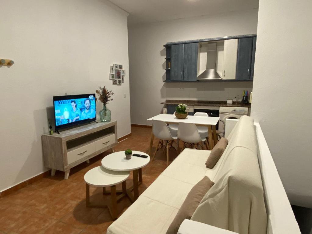 ein Wohnzimmer mit einem weißen Sofa und einem TV in der Unterkunft CASA DEL PEZ Vivienda a pie de calle en Agua Amarga a 250 metros de la playa in Agua Amarga