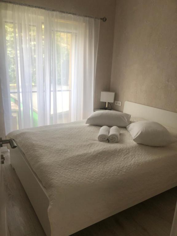 a bedroom with a large white bed with a window at Vila KOPA Šventoji in Šventoji