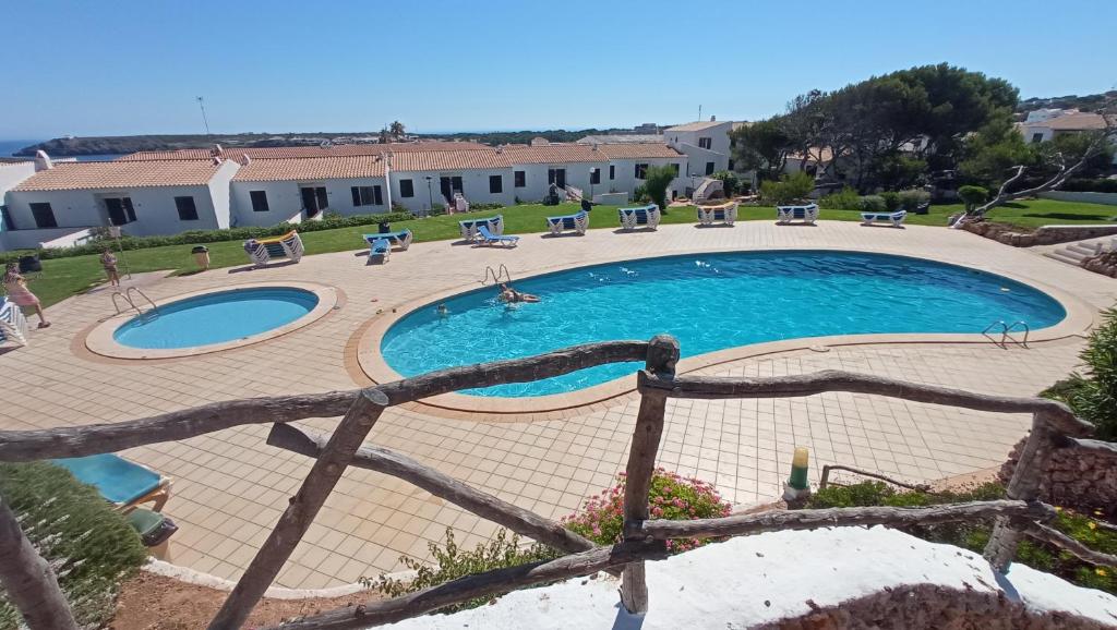 uma grande piscina com cadeiras e uma cerca em Costa Arenal 112 em Arenal d'en Castell