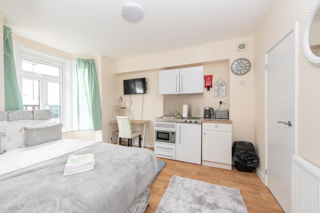 a bedroom with a white bed and a kitchen at Modern Studio Apartments in Castle St in Southampton