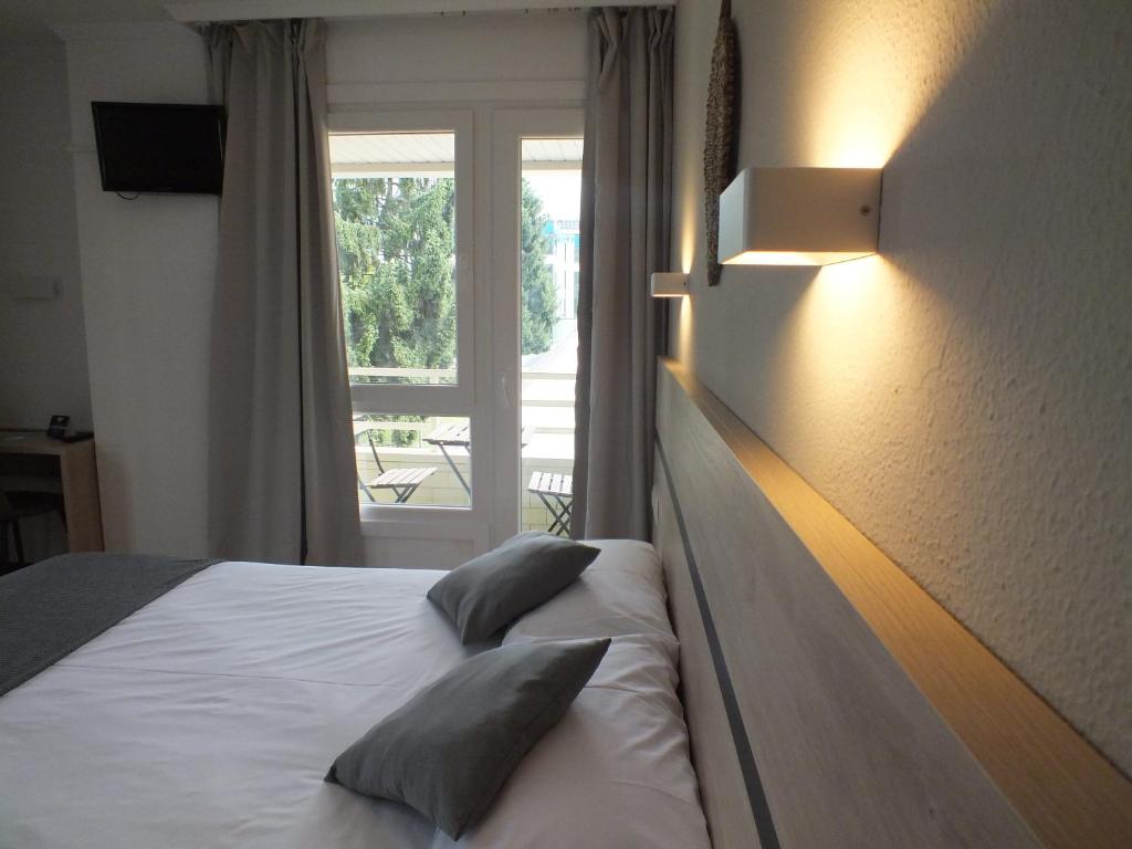 ein Schlafzimmer mit einem Bett mit Kissen und einem Fenster in der Unterkunft Hotel Alda Camiño Inglés in Ordes