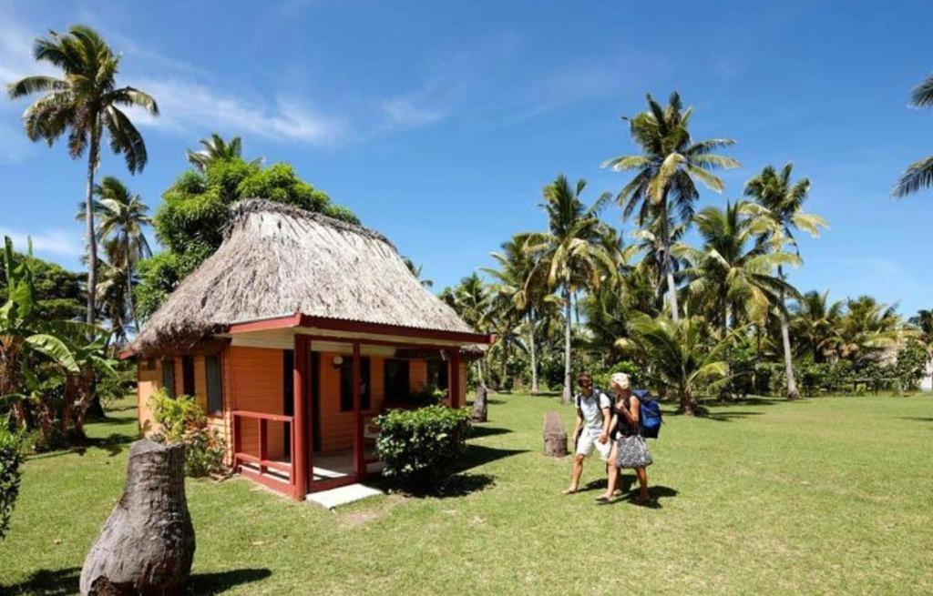 a group of people standing in front of a small building at Nabua Lodge in Nacula Island