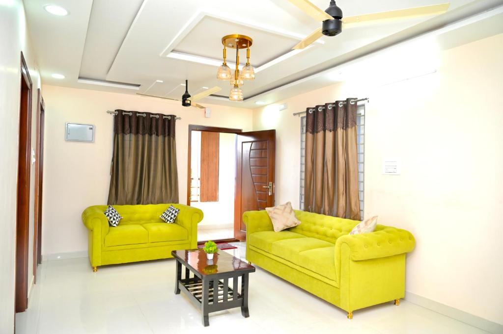 a living room with two yellow couches and a table at Srivari Homestay in Tirupati