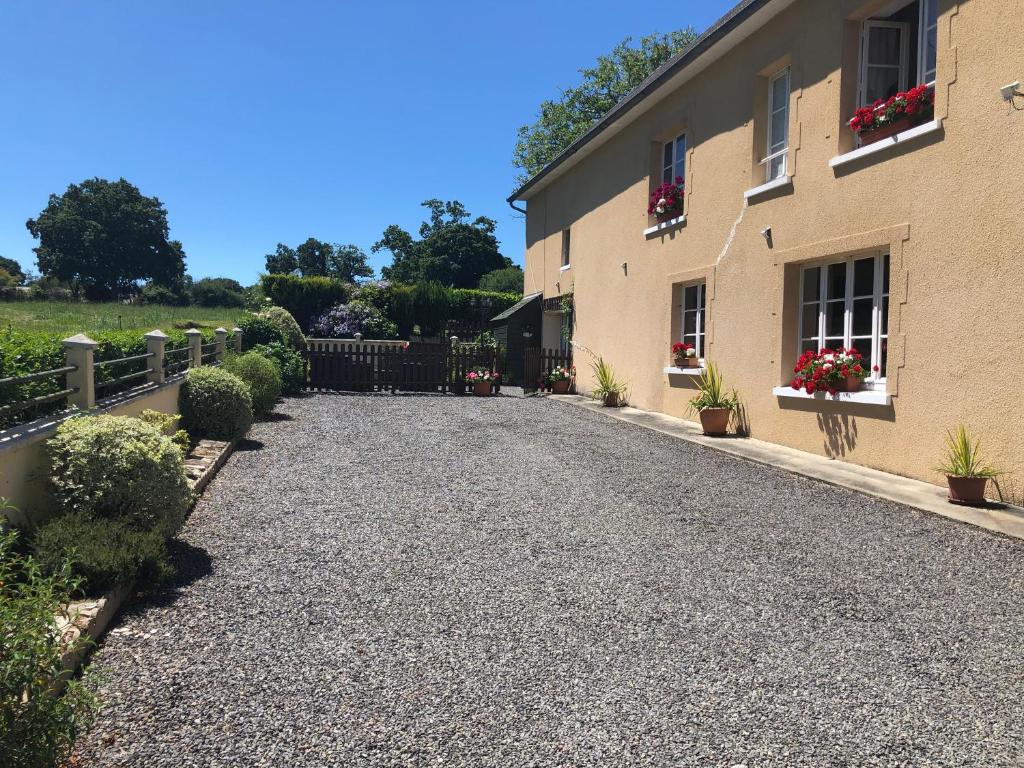 eine Kieseinfahrt neben einem Haus mit Topfpflanzen in der Unterkunft Le Grand Camelia in Saint-Martin-dʼAubigny