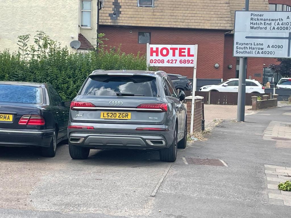 two cars parked in a parking lot with a hotel sign at Hotel in Harrow