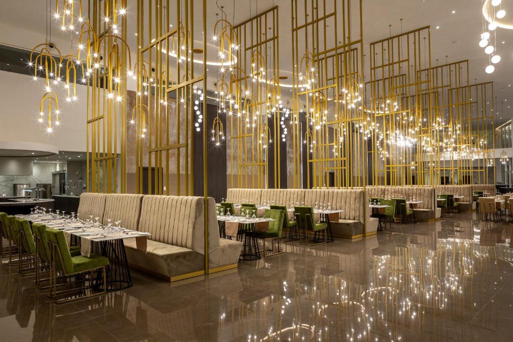 a restaurant with tables and chairs and a large chandelier at Chrysomare Beach Hotel & Resort in Ayia Napa