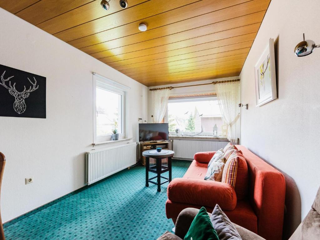 ブラウンラーゲにあるweißer Hirsch im Haus Sabineのリビングルーム(赤いソファ、テレビ付)