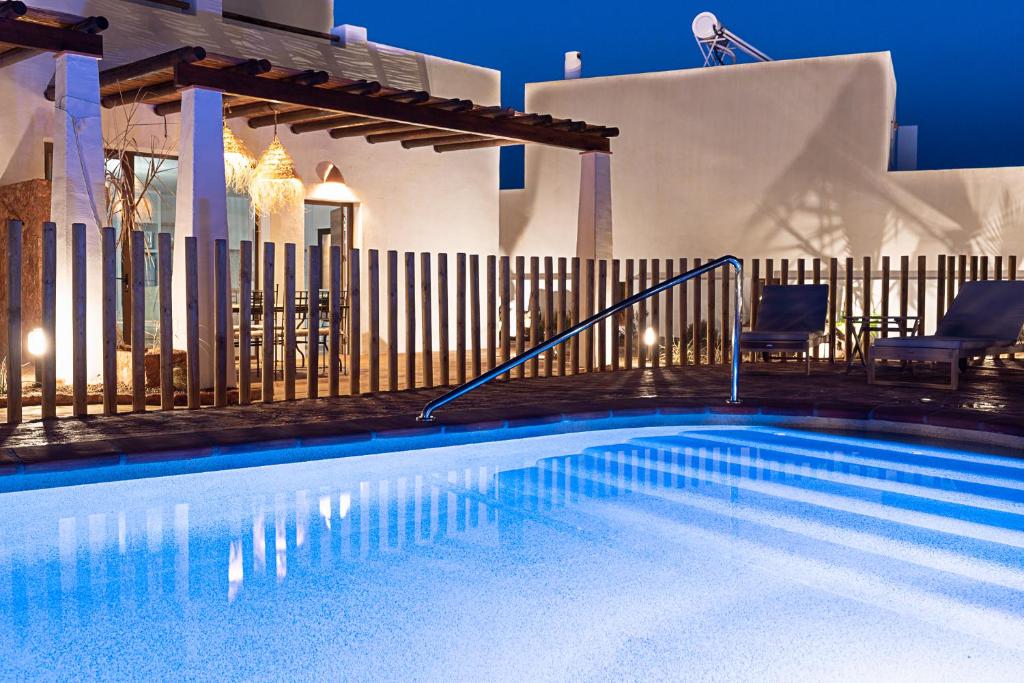 a swimming pool with two chairs and a fence at Las Musarañas - Complejo Rural in Rodalquilar