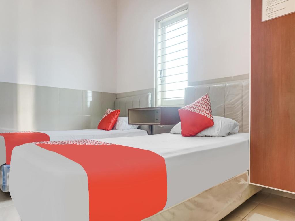 1 dormitorio con 2 camas y almohadas rojas y blancas en OYO 91316 Hh Guest House Makassar en Makassar