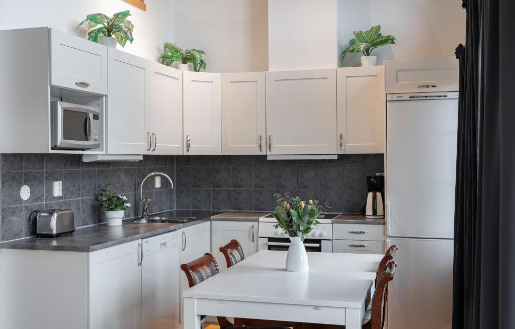 a kitchen with white cabinets and a table with flowers on it at Ekerum Village in Borgholm