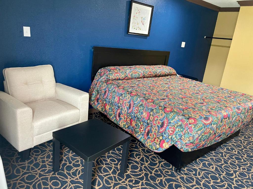 um quarto de hotel com uma cama e uma cadeira em Super 6 Inn em Carencro