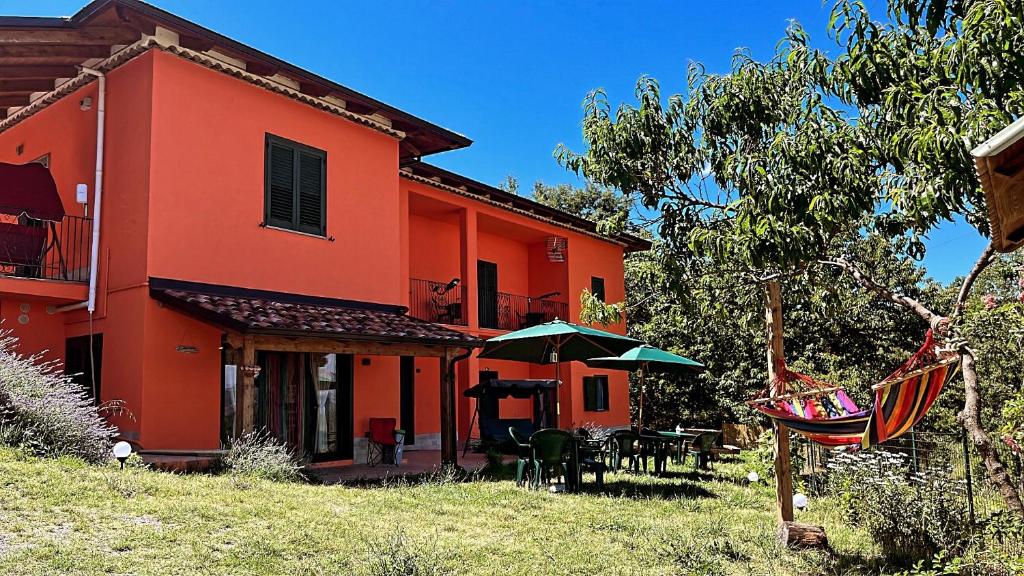 an orange house with a table and an umbrella at Residence Villa Gioia in San Severino Lucano