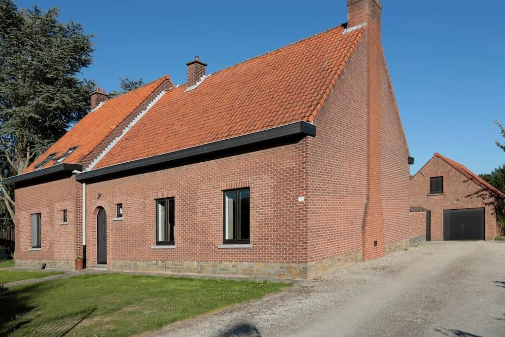 un grand bâtiment en briques avec un toit rouge dans l'établissement Huisje van de Meentocht, à Rumst