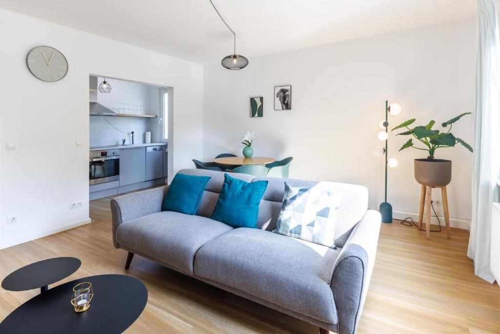 ein Wohnzimmer mit einem blauen Sofa und einer Küche in der Unterkunft Glück Auf Appartements Walter-Hohmann-Straße Essen in Essen