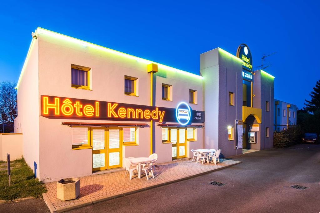 
a restaurant with a neon sign on the side of the building at Hôtel Kennedy Parc des Expositions in Tarbes
