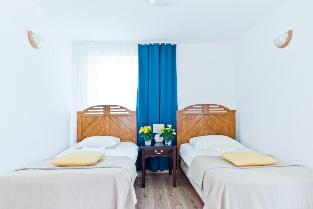2 camas en una habitación con cortinas azules en Ośrodek Wypoczynkowy Jantar, en Krynica Morska
