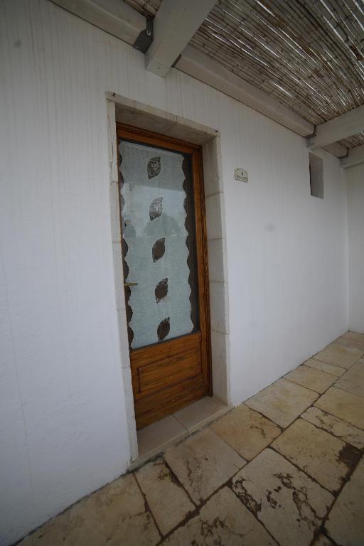 Una puerta de madera en una habitación blanca con suelo de baldosa. en Masseria Casamassima agriturismo, en Ostuni