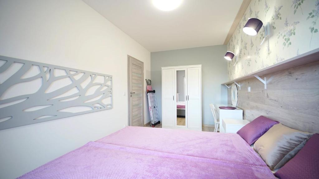 a bedroom with a pink bed with a pink blanket at Apartamenty EverySky - Kilińskiego 2 in Świeradów-Zdrój