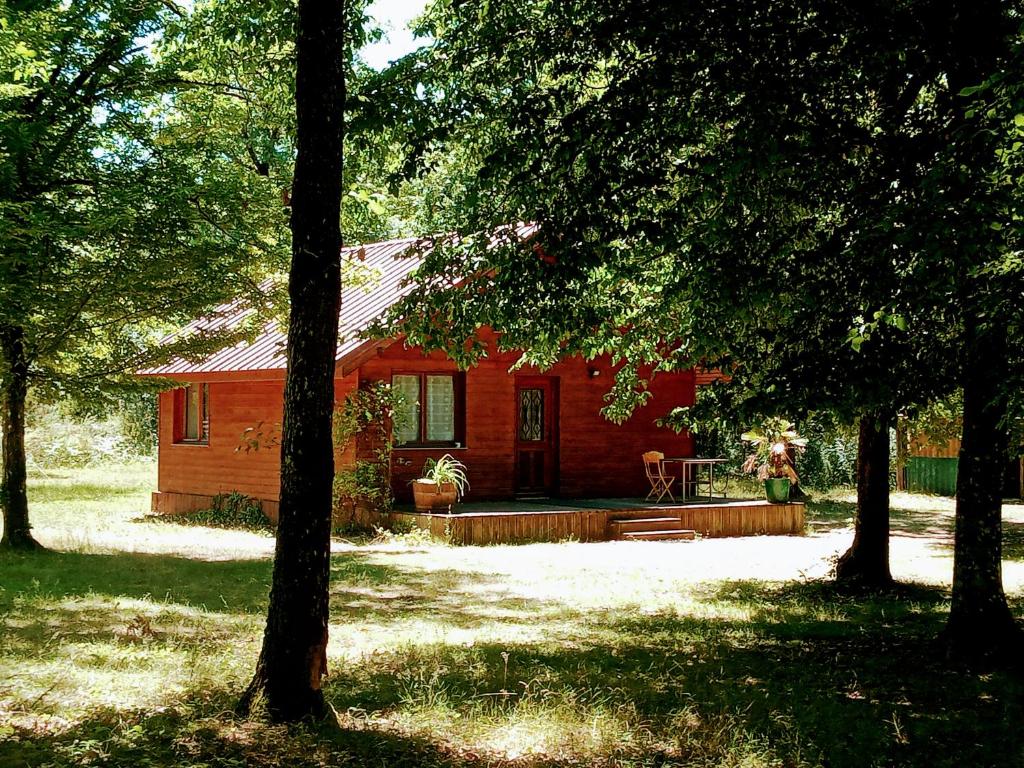 Chalet en forêt, brame du cerf في Valpuiseaux: كابينة حمراء وسط بعض الأشجار