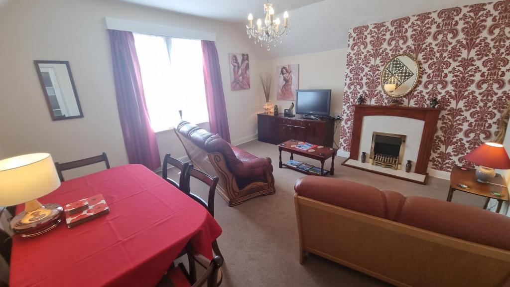 a living room with a red table and a fireplace at Cruden Villa - Second Floor Apartment in Scarborough