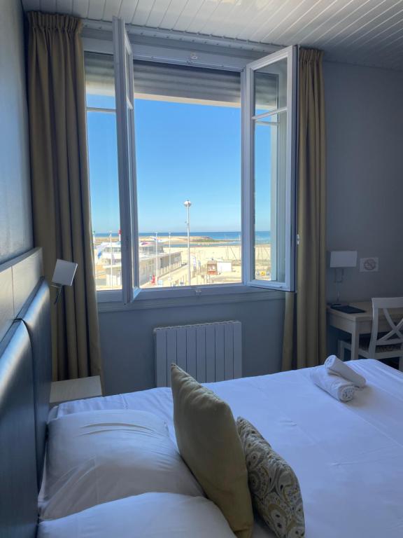 a bedroom with a bed with a view of the beach at Les Embruns in Trouville-sur-Mer