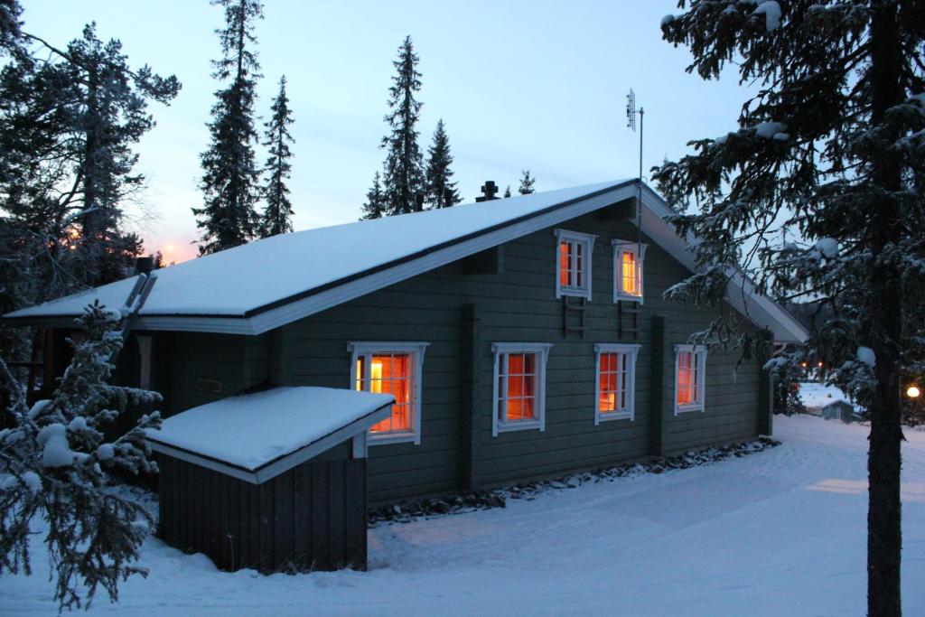 domek z bali na śniegu z włączonymi światłami w obiekcie Vuosselin Kruunu w mieście Ruka