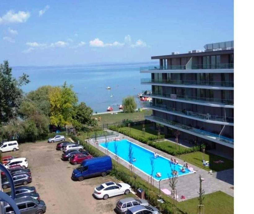 een parkeerplaats met auto's geparkeerd naast een groot gebouw bij Sunrise Apartman in Siófok