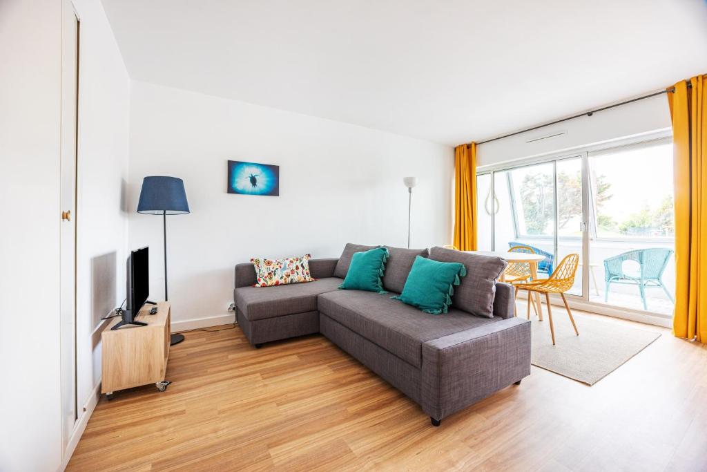ein Wohnzimmer mit einem Sofa und einem TV in der Unterkunft La Tortue Joyeuse - Appartement avec Loggia in Bernières-sur-Mer