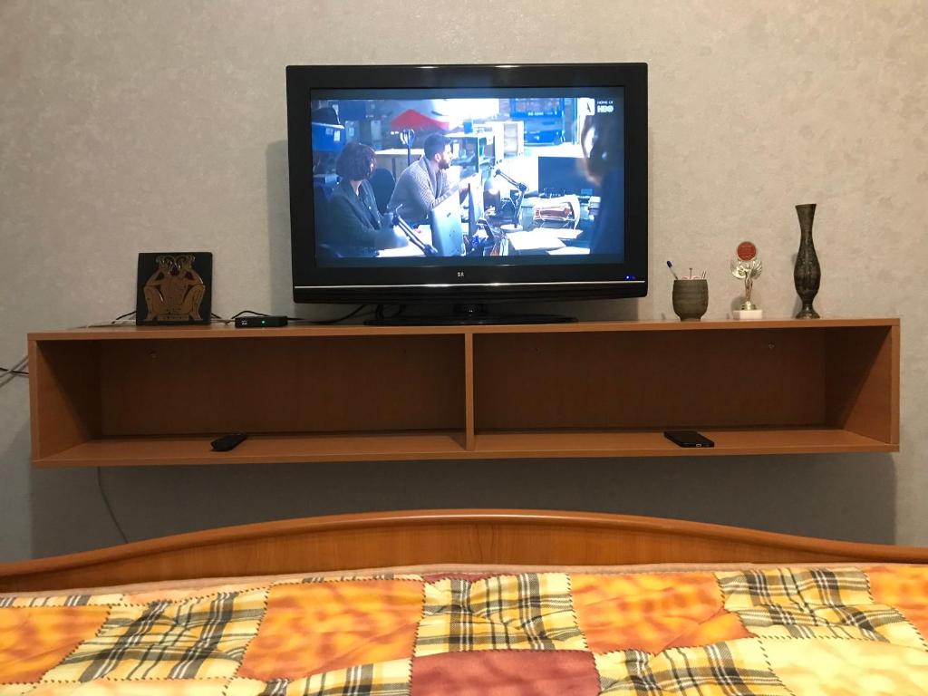 een televisie op een plank in een slaapkamer bij квартира на набережной in Alma-Ata