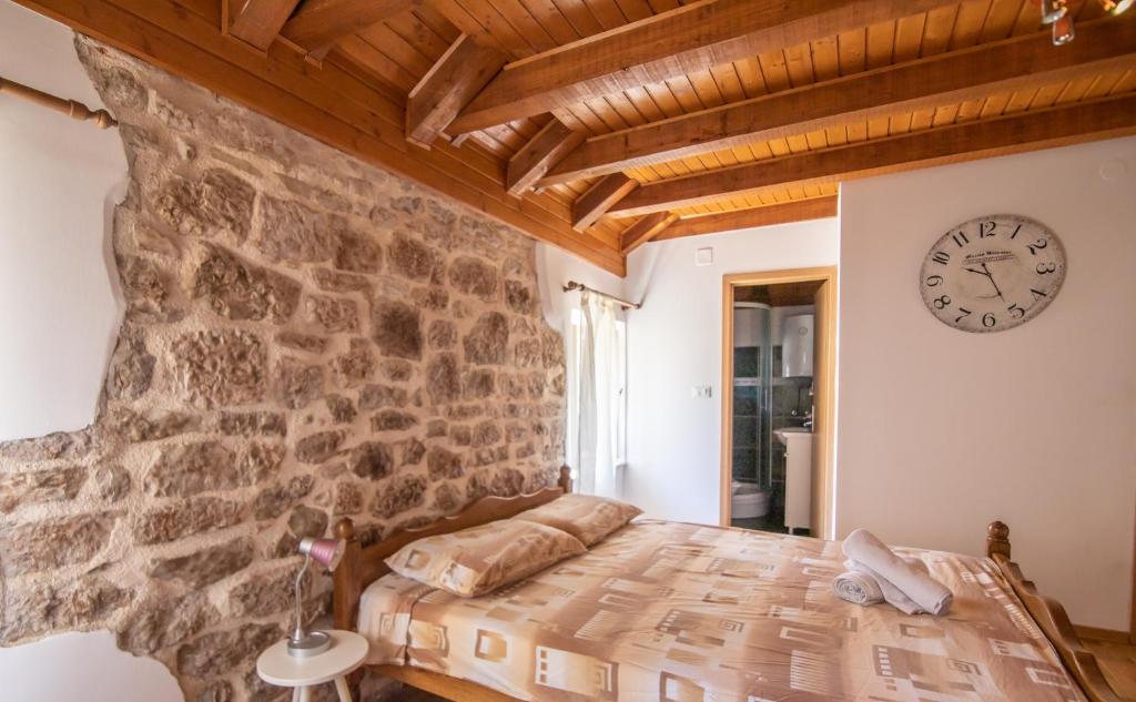 1 dormitorio con pared de piedra y reloj en la pared en Apartments Loriana, en Šibenik