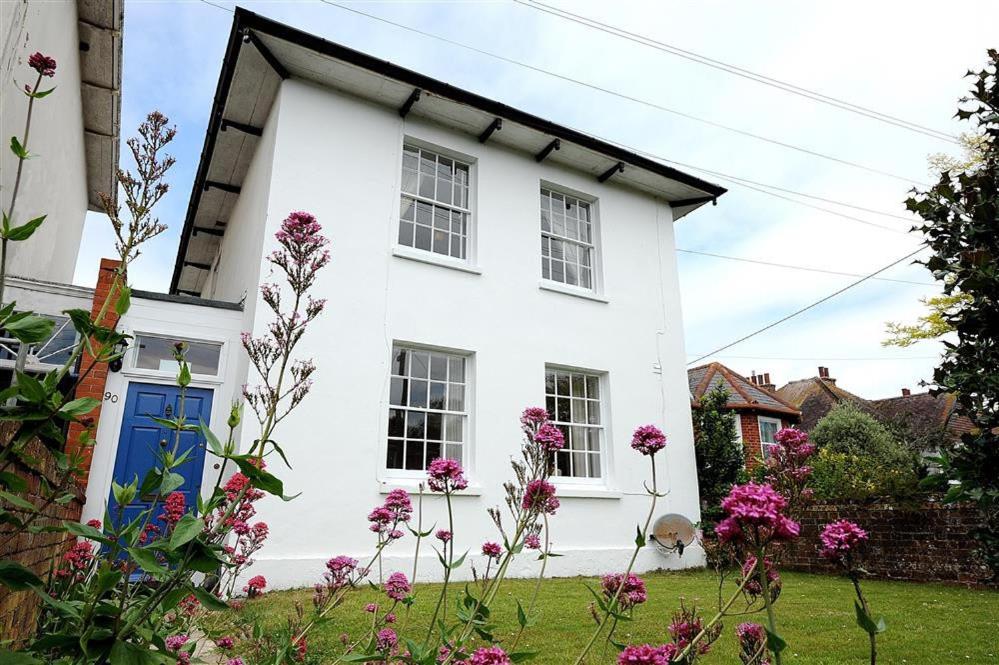 a white house with a blue door and pink flowers at The White House in Bridport