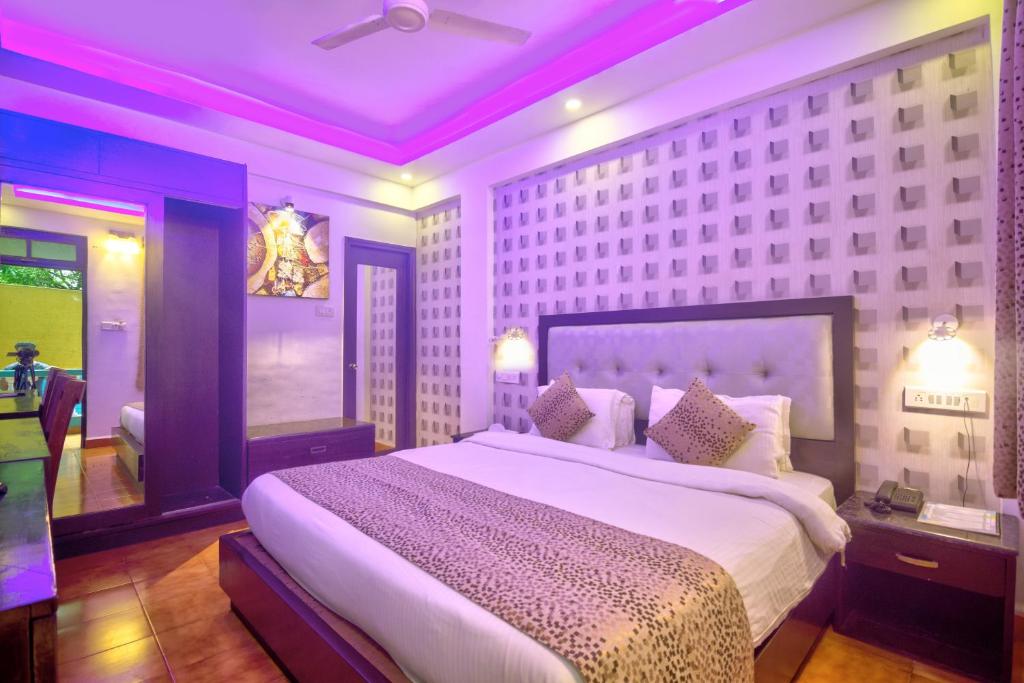 ein Schlafzimmer mit einem großen Bett mit violetter Beleuchtung in der Unterkunft Fusion Resorts in Candolim