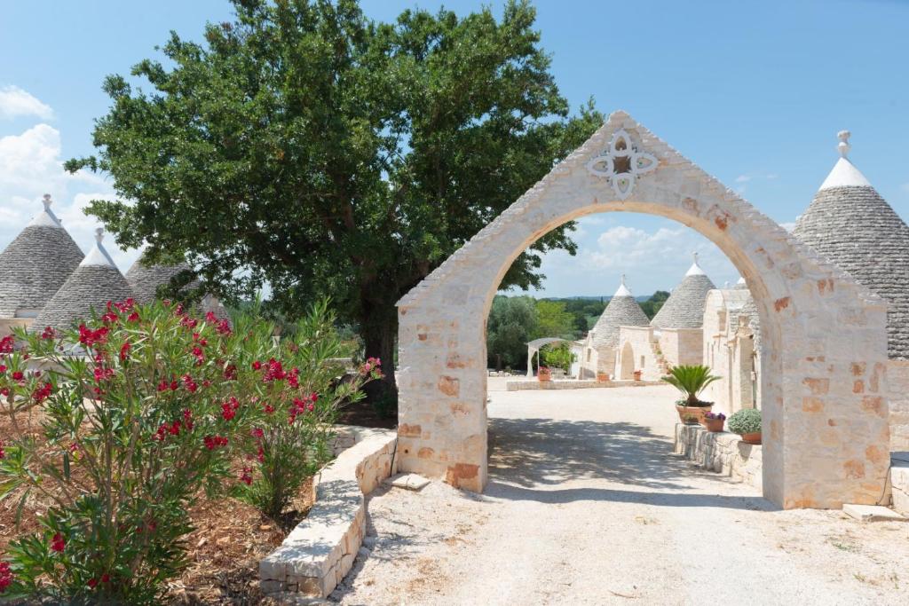 une arche dans un jardin avec des fleurs et un arbre dans l'établissement Trulli Vulés, à Ostuni