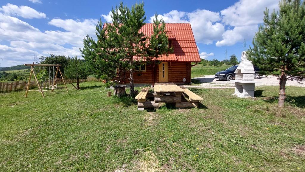 Cabaña de madera con mesa de picnic y parque infantil en VILA LENA en Kokin Brod