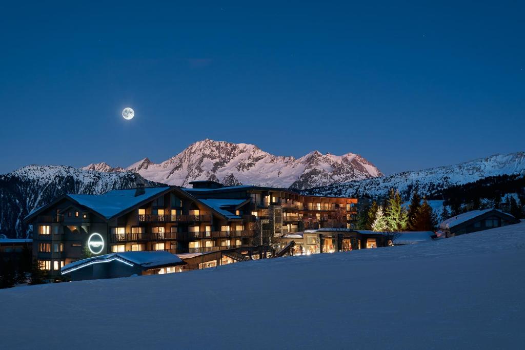 a large building in the snow at night with the moon at Hotel Annapurna in Courchevel