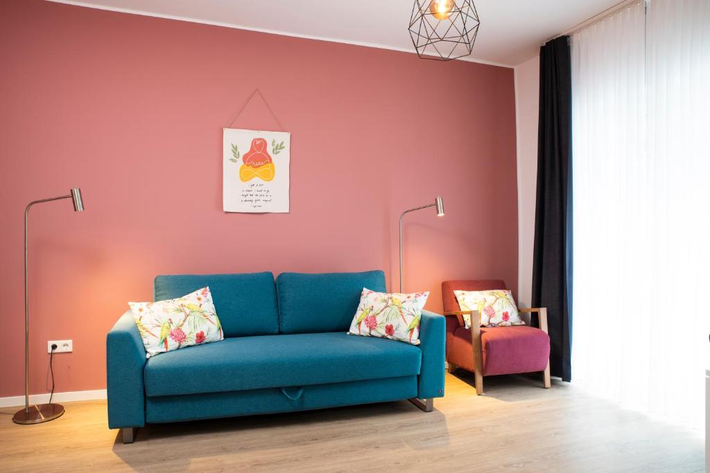 a living room with a blue couch and a pink wall at Villa am Bahnhof in Fulda in Fulda