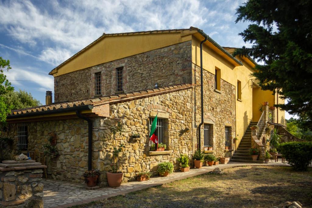 una antigua casa de piedra con una escalera delante de ella en CASE&COLLINE Bella Vista en Guardistallo