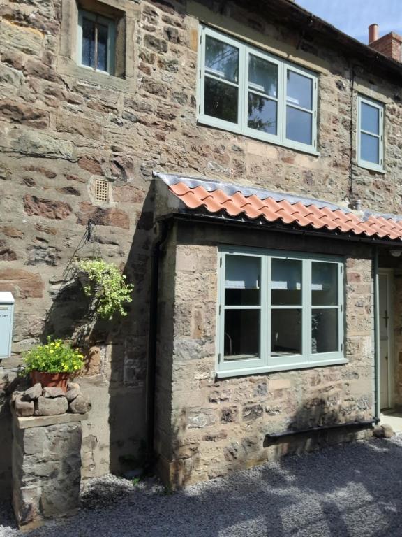 a stone house with a window and a roof at The Curtain 13th Century Cottage, Gilling West, Richmond in Gilling