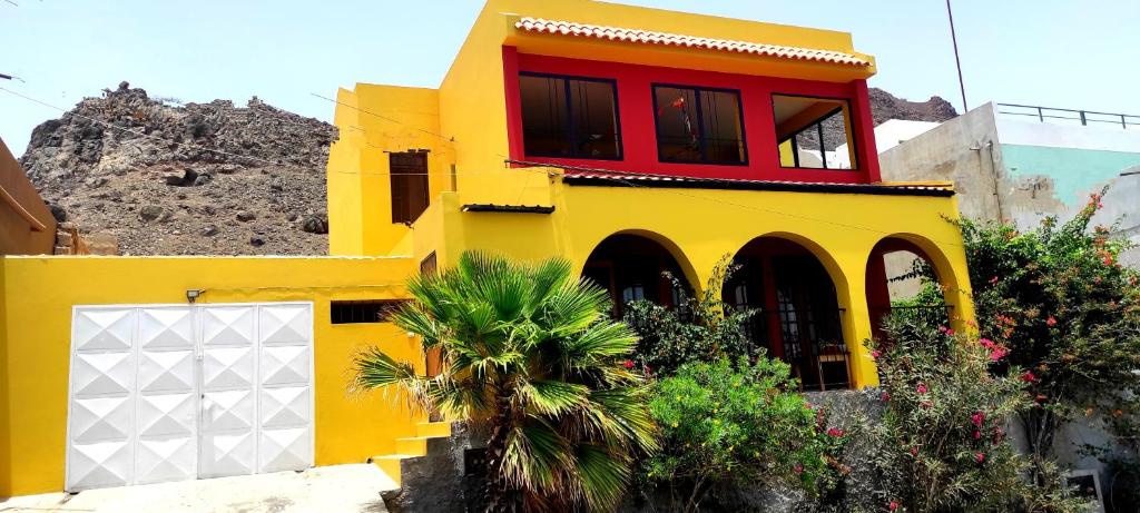 un edificio amarillo con una ventana roja. en Rose`s place, en Mindelo