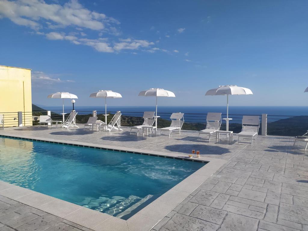 a swimming pool with chairs and umbrellas and the ocean at Tenuta Vallina - Golfo di Policastro in Tortorella