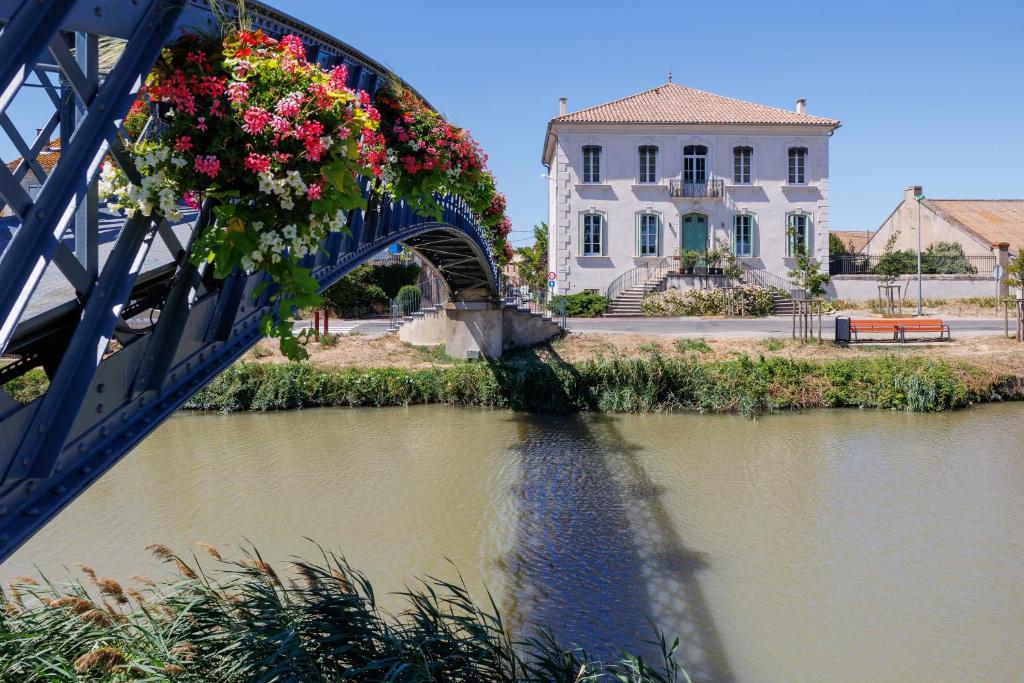 eine Brücke mit Blumen über einen Fluss in der Unterkunft La Passerelle du Canal in Sallèles-dʼAude