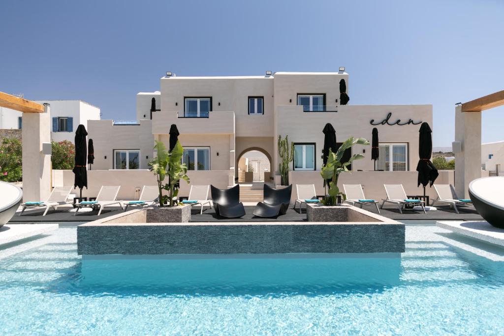 un complexe avec une piscine entourée de chaises et un bâtiment dans l'établissement Eden Beachfront Residences & Suites, à Kastraki Naxou