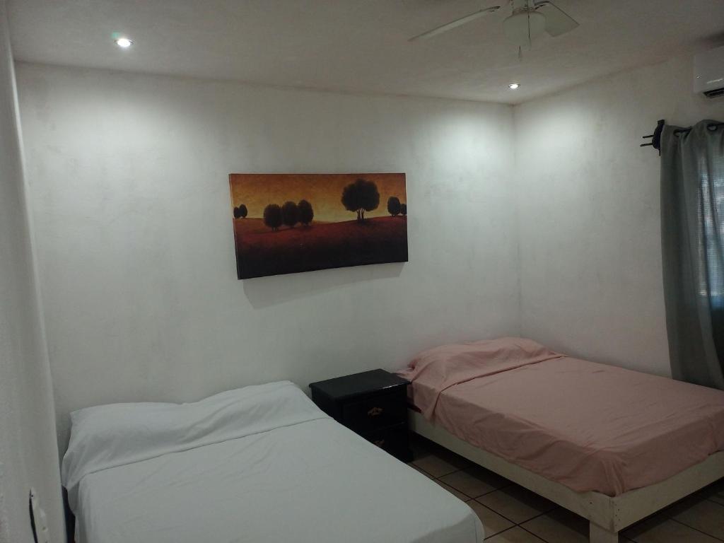 Cette chambre comprend deux lits et un tableau mural. dans l'établissement Apts. LOSSANTOS, à Matamoros