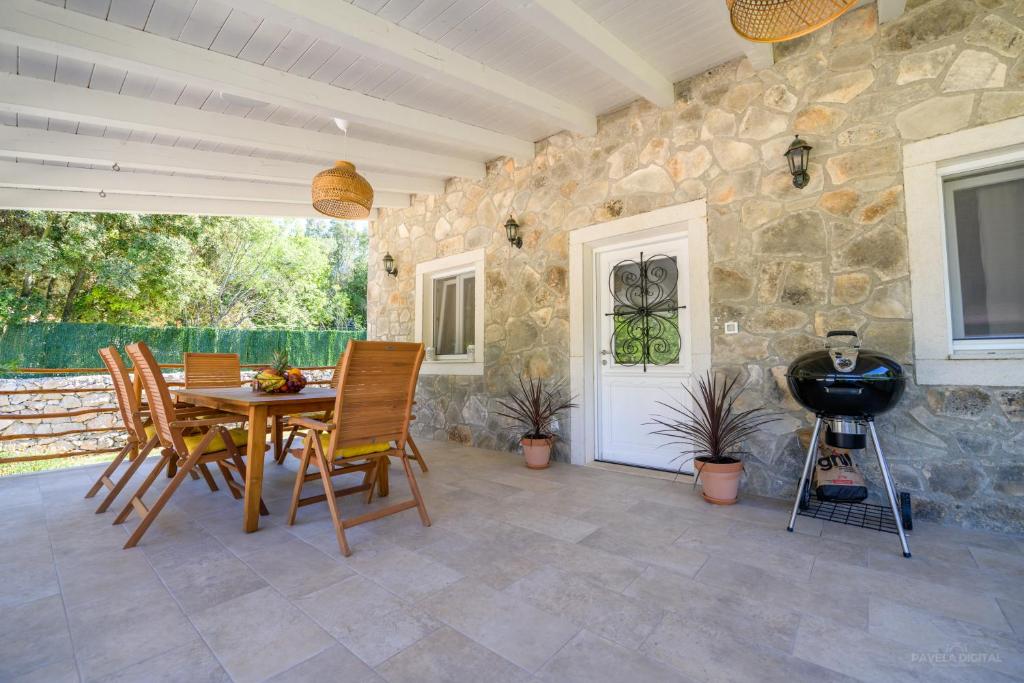 ein Esszimmer mit einem Tisch, Stühlen und einer Steinmauer in der Unterkunft STONE HOUSE MAGALI in Sveti Jakov