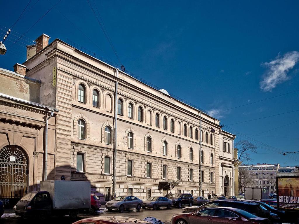 un gran edificio con coches estacionados frente a él en Peter Hostel, en San Petersburgo