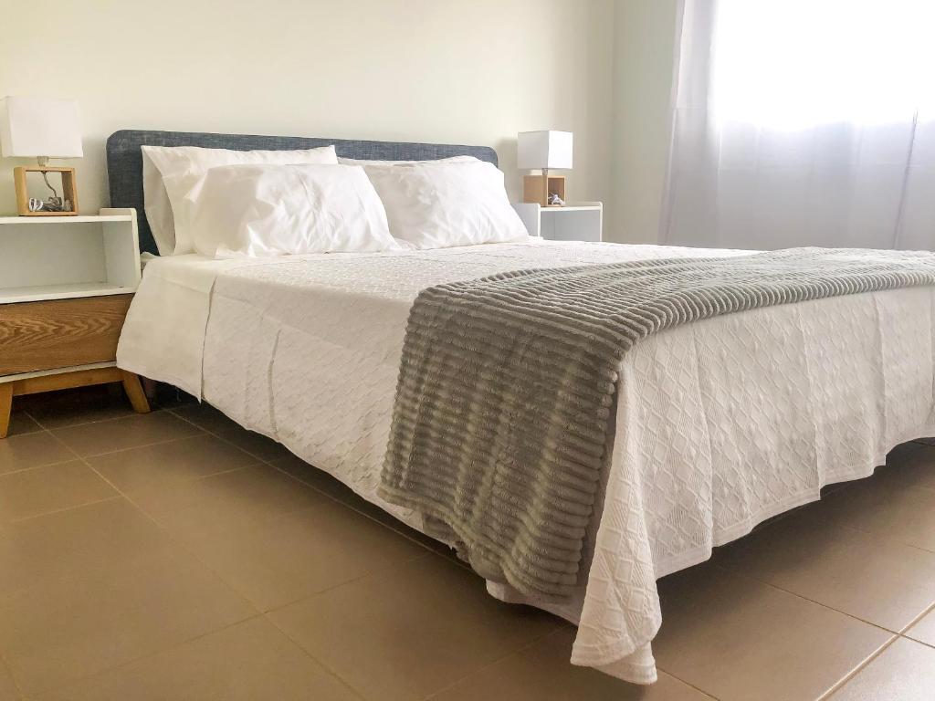 ein Schlafzimmer mit einem großen Bett mit weißen Laken und Kissen in der Unterkunft Brand New Chic Appt in Mindelo at Great Rates in Mindelo