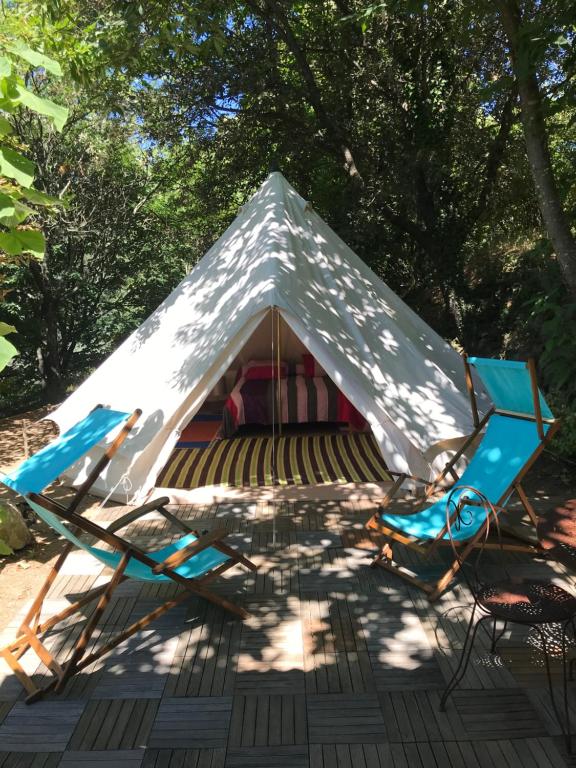 a tent with two chairs and a table at LE PETIT REFUGE DU VAL D’EMERAUDE in Soudorgues