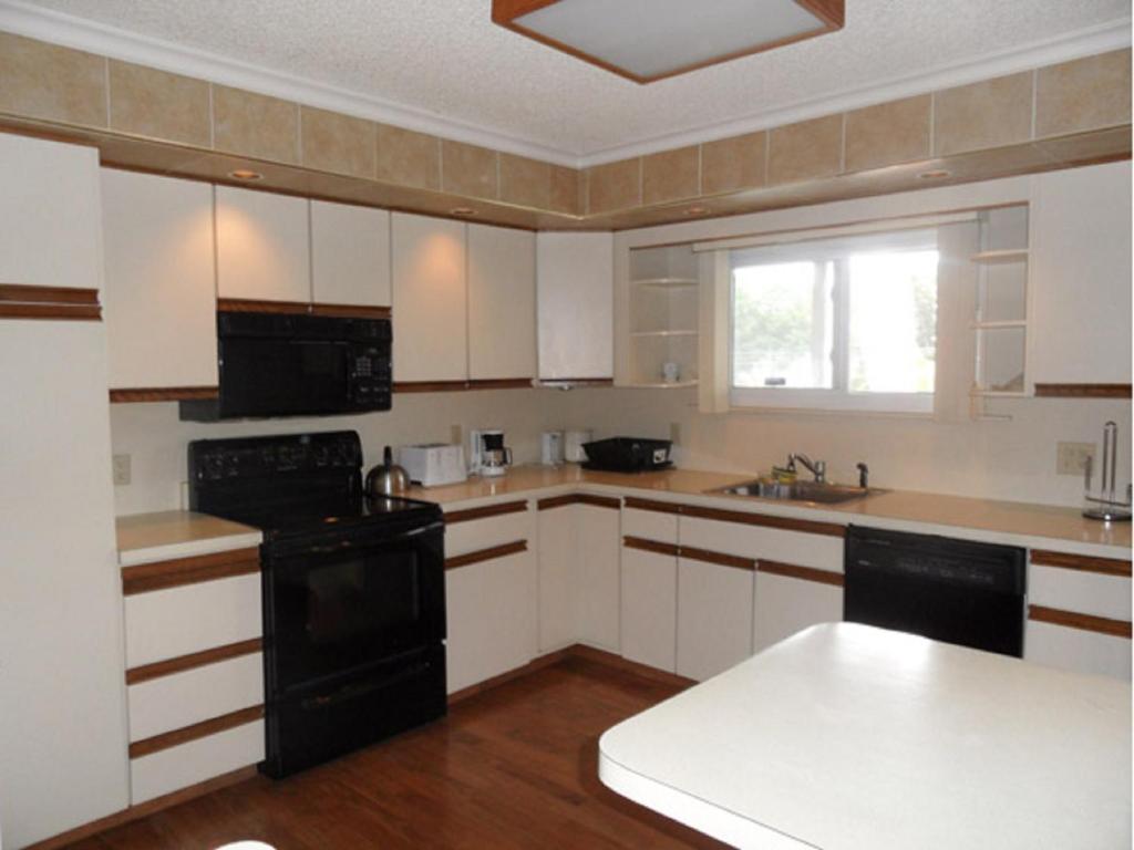 uma cozinha com armários brancos e electrodomésticos pretos em Pinebrook - Three Bedroom House em Lake George
