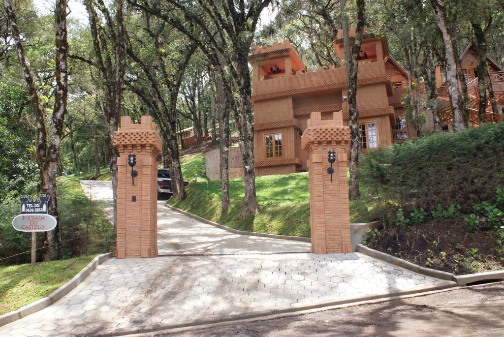 a house with a gate in the middle of a driveway at Pousada do Castelo in Monte Verde