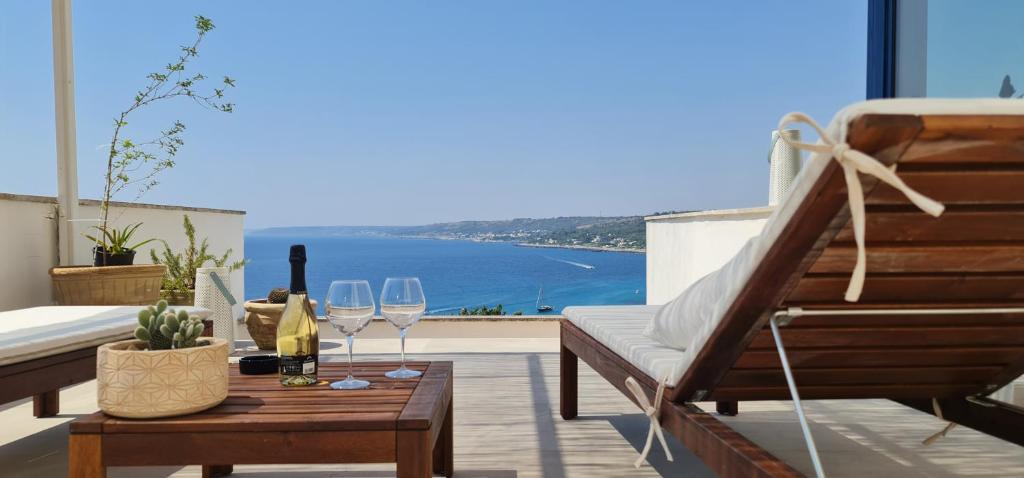 Un balcón con una mesa con copas de vino y vistas al océano. en Bona Vitae - Attico Vista Mare Castro, en Castro di Lecce